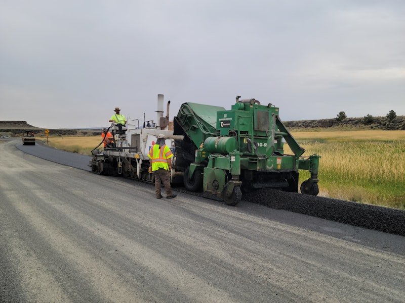 Two workers repairing an asphalt road surface